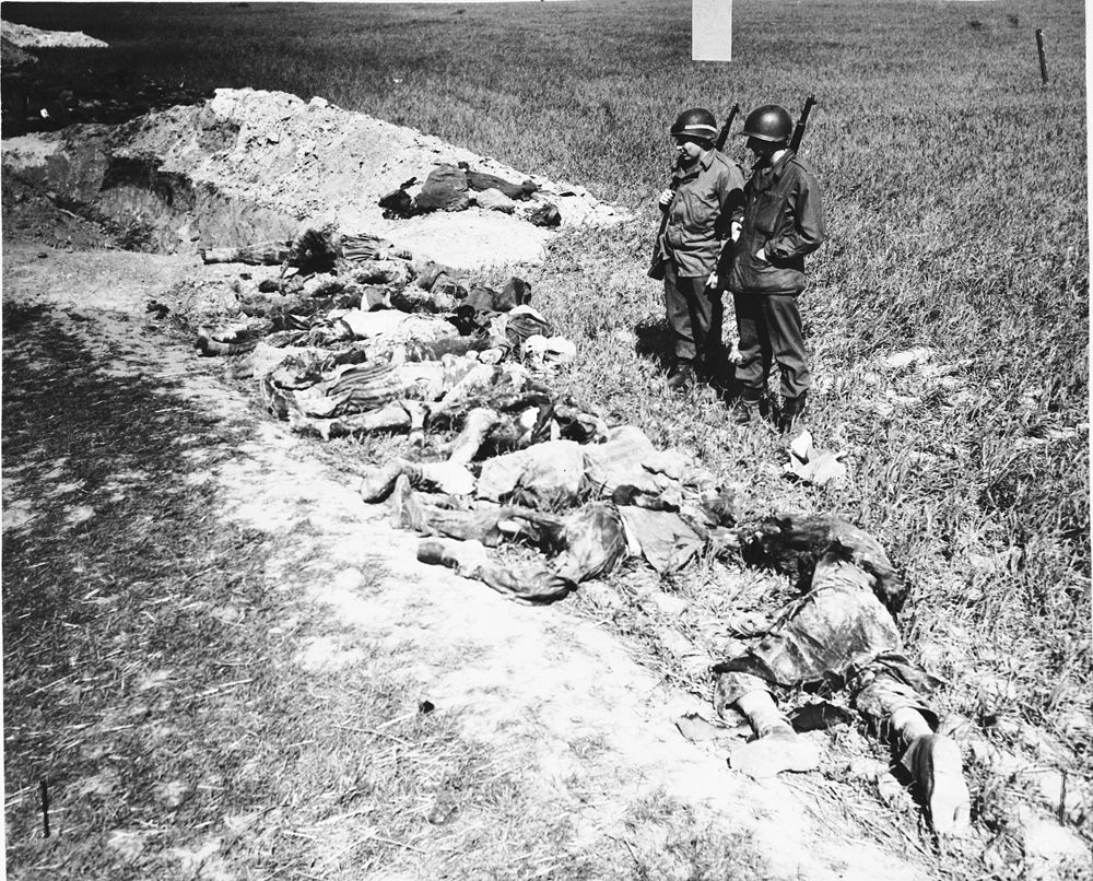 American soldiers look at the exhumed bodies of prisoners who were burned alive in a barn outsid.jpg
