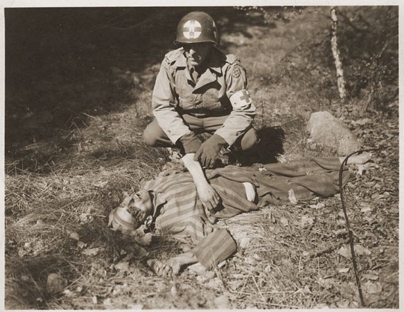 An American soldier kneels by the corpse of a prisoner on the roadside near Gardelegen0.jpg
