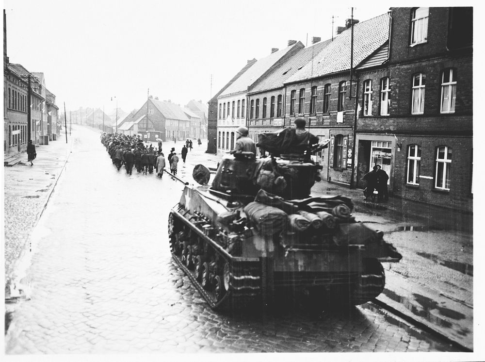 An American tank follows German civilians from Gardelegen who are marching to the barn just outs.jpg