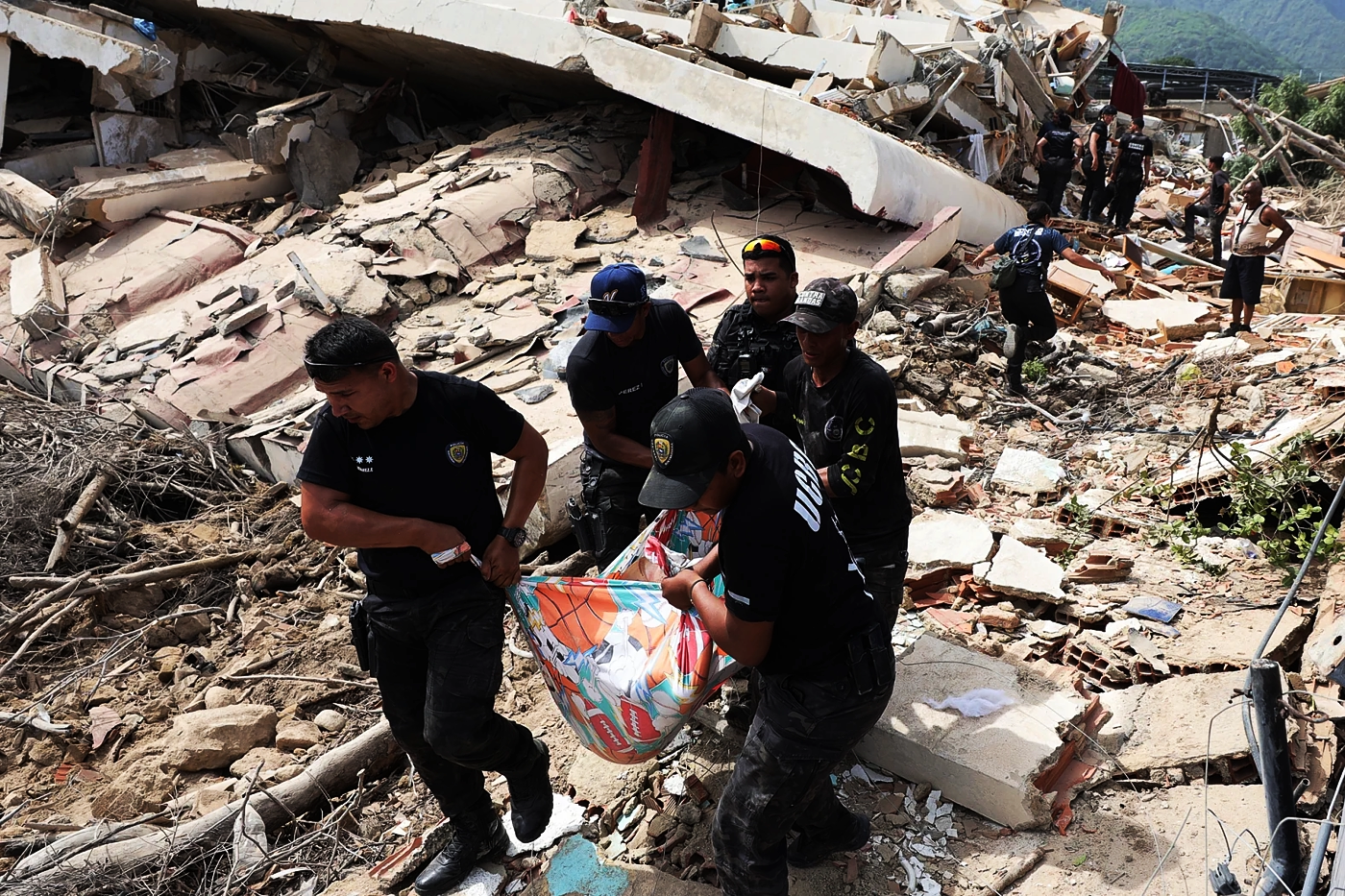 Earthquake aftermath, police officers remove a body as rescue efforts continue 1, La Guaira, ...webp