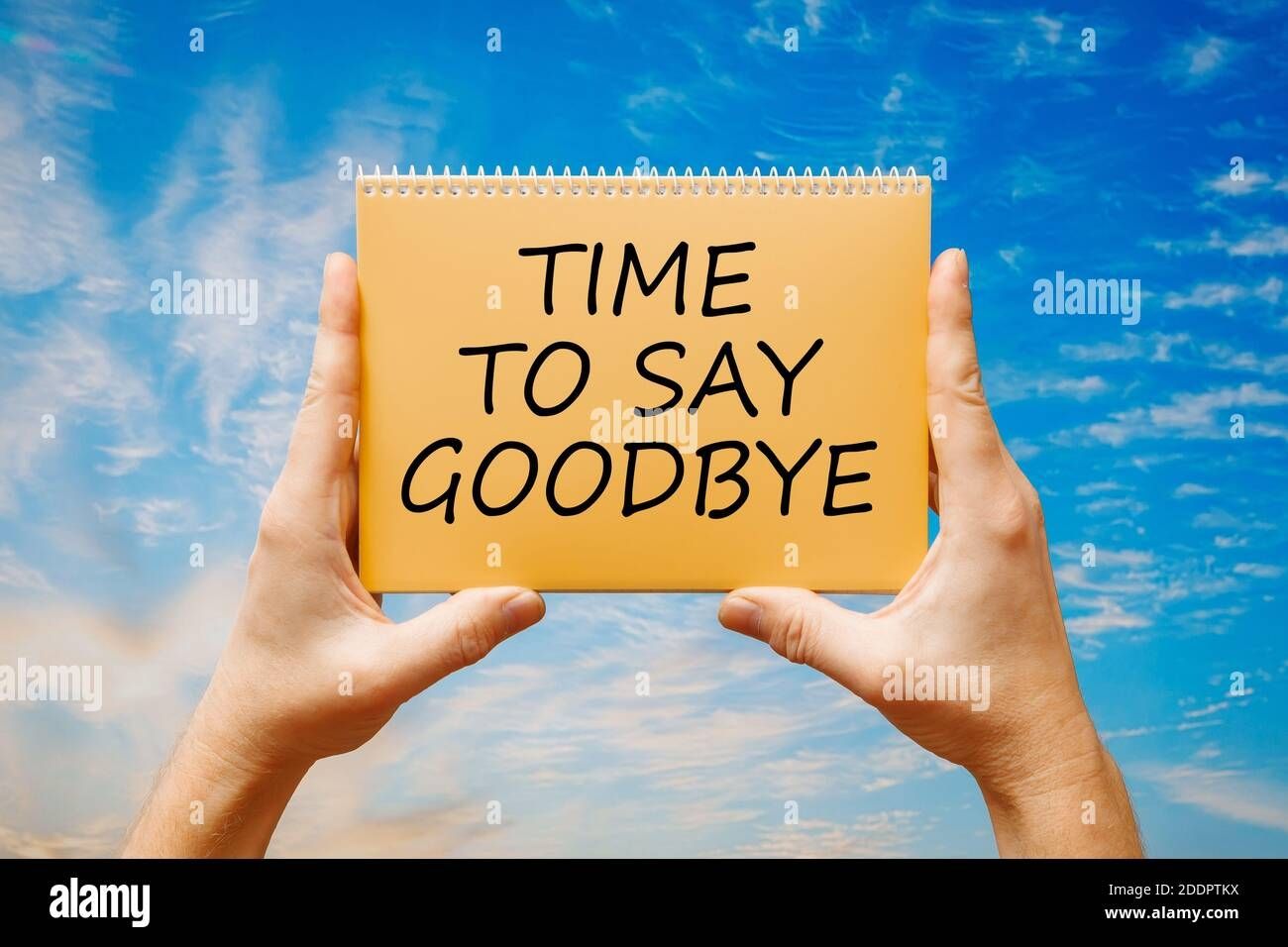 man-holding-a-card-with-text-time-to-say-goodbye-on-the-background-of-a-blue-sky-2DDPTKX.jpg