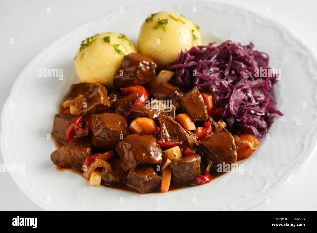 wurziger-wildschwein-oder-reh-gulasch-in-einem-reichhaltigen-sosse-mit-klossen-und-rotkohl-au...webp