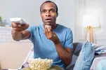 nice-astonished-handsome-man-eating-popcorn-being-involved-movie-while-watching-tv_259150-24288.webp